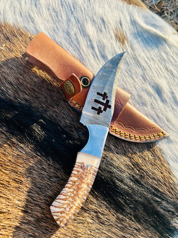 Damascus fixed blade knife resting on wooden stump outdoors